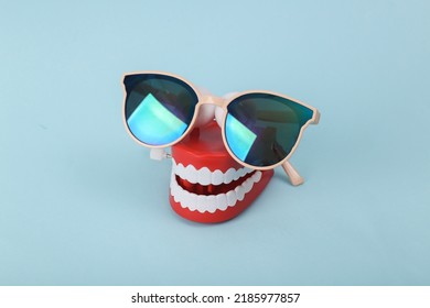 Funny Toy Clockwork Jumping Teeth With Sunglasses On Blue Background.
