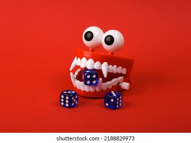 Funny Toy Clockwork Jumping Teeth With Eyes And Dice On Red Background.