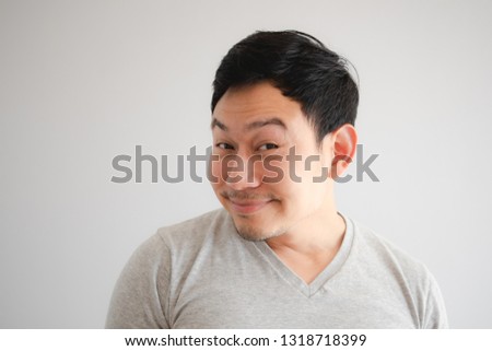 Funny tricky awkward smirk face of Asian man in grey t-shirt.