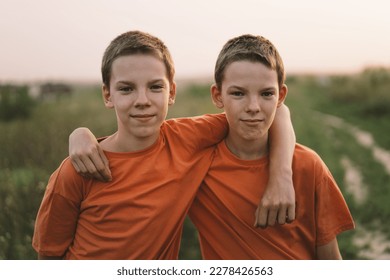 Funny twin brother boys in orange t-shirt playing outdoors on field at sunset. Happy children, lifestyle. - Powered by Shutterstock