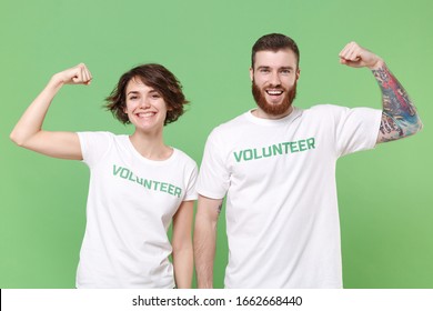 Funny two young friends couple in white volunteer t-shirt isolated on pastel green background in studio. Voluntary free work assistance help charity grace teamwork concept. Showing biceps, muscles - Shutterstock ID 1662668440