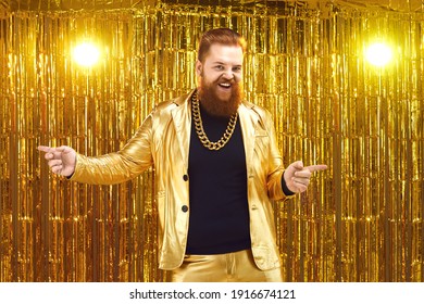 Funny Uninhibited Plus Size Young Man With Ginger Beard And Mustache In Golden Suit With Bling Gold Neck Chain Performing On Stage At Disco Party In Night Club, Dancing, Singing Songs And Having Fun