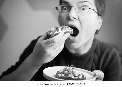 Funny Upclose View Of Caucasian Woman Eating Avocado Toast Looking Into Camera, Horizontal Black And White Shot