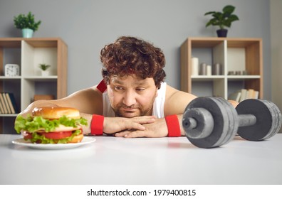 Funny Upset Depressed Fat Athlete Choosing Between Gym Dumbbell And Delicious Cheeseburger. Concept Of Sport, Choice, Willpower, Healthy Weight Loss Fitness Exercise Vs Yummy Unhealthy Fast Food Diet