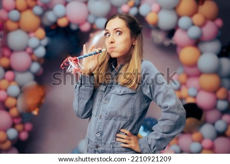 
Funny Woman Blowing a Party Whistle for her Celebratory Event. Happy cheerful girl having fun at her anniversary event
