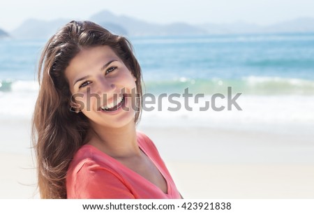 Funny woman with dark hair at beach with ocean and blue sky in the background