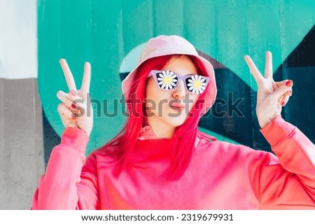 Funny woman with duck lips in sunglasses with flowers stickers making V sign by fingers. Playful woman with pink hair,bucket hat and magenta sweatshirt. Vanilla Girl. Kawaii vibes. Candy colors design