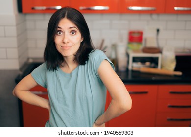 Funny Woman With Hands On Hips Standing In The Kitchen. Hungry Person Thinking What To Eat 
