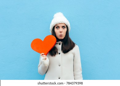 Funny Woman In Love Holding A Heart On Blue Background. Surprised Valentine Girl Having A Sudden Crush 
