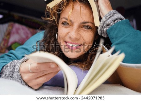 A funny woman reading a book laying in the bed. World book day
