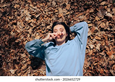 
Funny Woman Sitting On Dry Autumn Leaves. Young Quirky Person Having A Sense A Humor Making Faces
