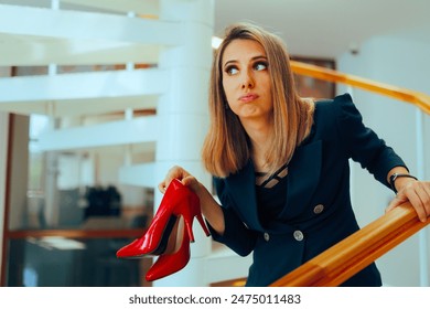
Funny Woman Taking off High Heels in the Office. Barefoot secretary feeling ashamed trying to keep quiet 
