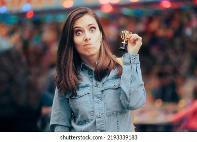 
Funny Woman Winning a Small Trophy at Funfair Contest. Sore loser receiving a participation consolation prize
