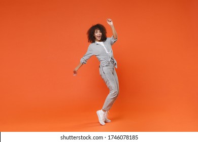 Funny young african american woman girl in gray casual clothes posing isolated on orange background in studio. People lifestyle concept. Mock up copy space. Dancing, standing on toes, rising hands