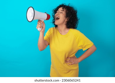 Funny young arab woman wearing yellow T-shirt over blue background People sincere emotions lifestyle concept. Mock up copy space. Screaming in megaphone. - Powered by Shutterstock