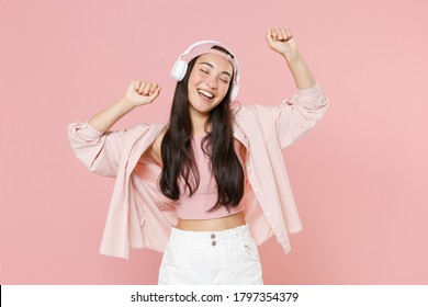 Funny young asian woman in casual clothes cap posing isolated on pastel pink background studio portrait. People lifestyle concept. Mock up copy space. Listening music with headphones, dancing - Powered by Shutterstock