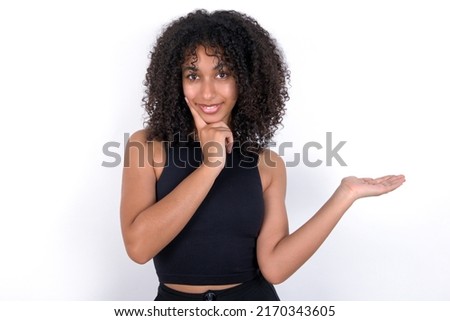 Funny Young beautiful girl with afro hairstyle wearing black t-shirt over white background hold open palm new product great proposition