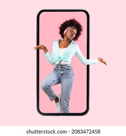 Funny young black woman coming out off big cellphone screen, jumping and dancing on pink studio background, collage, vertical banner. Excited hipster lady recommending cool new mobile application