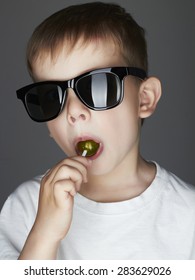 Funny Young Boy Eating A Lollipop.Fashionable Child In Sunglasses