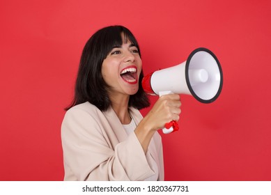 
Funny young brunette businesswoman posing isolated on pastel red wall background studio portrait. People sincere emotions lifestyle concept. Mock up copy space. Screaming in megaphone