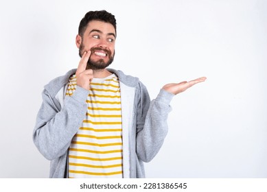 Funny Young caucasian mán wearing trendy clothes over white background holding open palm new product. I wanna buy it!