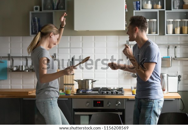 Funny young couple dancing to music together\
enjoying cooking in the kitchen, man and woman in love having fun\
preparing breakfast food feeling happy and carefree on weekend\
lifestyle at home