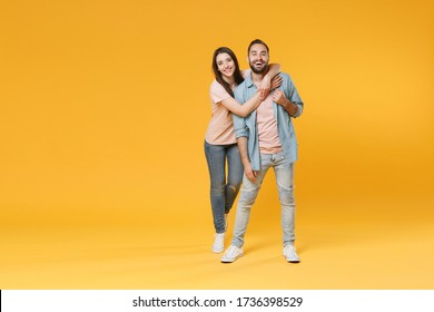 Funny Young Couple Two Friends Guy Girl In Pastel Blue Casual Clothes Posing Isolated On Yellow Wall Background Studio Portrait. People Lifestyle Concept. Mock Up Copy Space. Hugging, Looking Camera