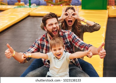 Funny Young Family With Their Little Son Spending Time On A Trampoline Together At The Entertainment Centre