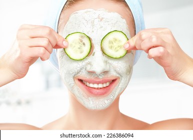 Funny young girl with a mask for skin face and cucumbers on eyes - Powered by Shutterstock