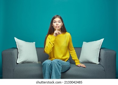 Funny Young Girl Show Silence Gesture Ask To Be Quiet, Sitting On Sofa, Watching Modern Interesting Movie Or Series