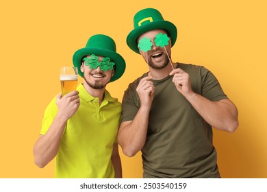 Funny young men in leprechaun's hats with beer and clovers on yellow background. St. Patrick's Day celebration - Powered by Shutterstock