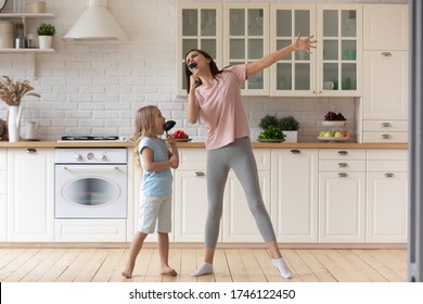 Funny Young Mom Or Nanny Play Sing Entertain Using Kitchen Appliances With Little Preschooler Girl Child, Smiling Overjoyed Mother Have Fun Enjoy Family Leisure Weekend With Small Daughter At Home