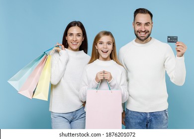 Funny Young Parents Mom Dad With Child Kid Daughter Teen Girl In Sweaters Hold Package Bags With Purchases After Shopping Credit Bank Card Isolated On Blue Background. Family Day Parenthood Concept