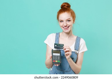 Funny young redhead girl she in casual denim clothes isolated on blue turquoise background. People lifestyle concept. Hold wireless modern bank payment terminal to process acquire credit card payments - Shutterstock ID 2249060809