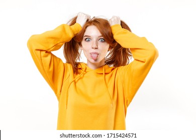 Funny young redhead woman girl in yellow hoodie posing isolated on white background studio portrait. People lifestyle concept. Mock up copy space. Having fun hold hair like ponytails, showing tongue