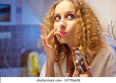 Funny Young Woman Eating Sweet Cake In The Kitchen At Night