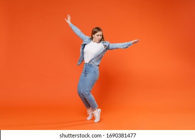 Funny young woman girl in casual denim clothes posing isolated on orange background studio portrait. People emotions lifestyle concept. Mock up copy space. Dancing, spreading hands, standing on toes - Shutterstock ID 1690381477