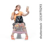 Funny young woman with glasses takes a selfie sitting on the toilet and holding a roll of toilet paper in her hand, isolated on white background