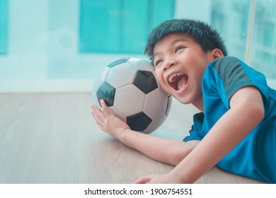 Funy Young Asian Fußball Spieler Kind schläft auf einem Fußball unter seinem Kopf.