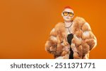 Fur Coat Fashion and Luxury style. Glamorous asian woman with short haircut and vivid orange hair posing in big stylish sunglasses and expensive fox fur coat on an orange studio background.  