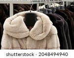 Fur coats in a row on a hanger in the store. Female fashion, natural fur clothes in sale