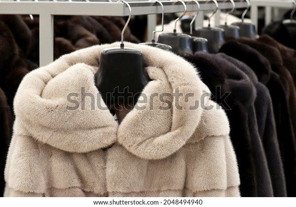 Fur coats in a row on a hanger in the\
store. Female fashion, natural fur clothes in\
sale