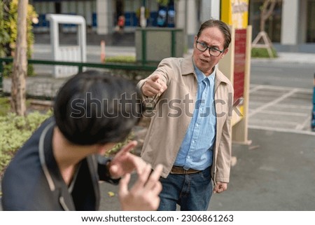 A furious asian man confronts and corners a frightened guy in public during a chance encounter. Accusing someone of cheating, theft or other grievances. Stock photo © 