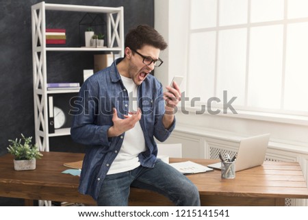 Furious businessman gesturing hands and solving problem while talking on smartphone. Angry executive manager arguing during mobile conversation, copy space