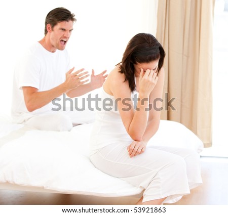 Furious couple having an argument sitting on their bed