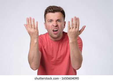 Furious, enraged man with grumpy grimace on his face,with mouth opened in shout, ready to argue. Studio shot - Shutterstock ID 1650604090