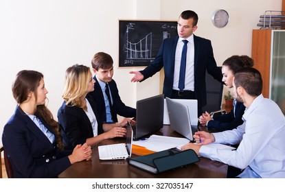 Furious head of company and frightened subordinate officials indoors. Focus on the left man - Shutterstock ID 327035147