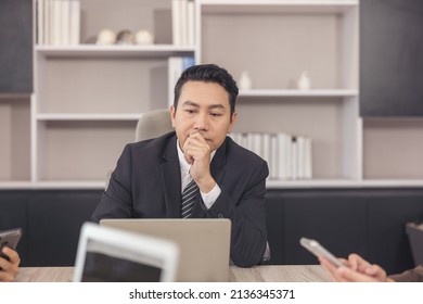 A Furious Male CEO Or Boss Sits At His Desk At The Office, Upset And Frustrated By A Bad Internet News Message On The Computer. A Melancholy Businessman 