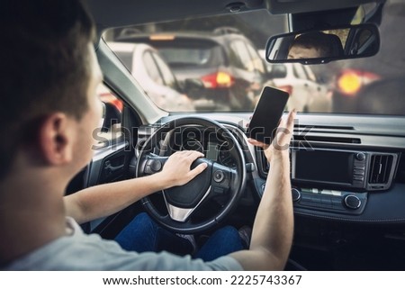 Furious man driver honking the car horn angry on the traffic jam ahead. Aggressive guy unsafe driving while using his phone in front of the steering wheel, violating the rules