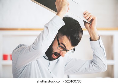 Furious Man At Workplace Throwning His Laptop. Anger Issues And Stress Concept